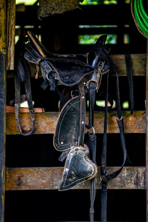 Old horse saddles hanging on a wooden fence. Vintage style.の写真素材