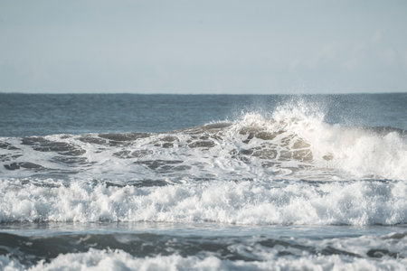 Beautiful view of the ocean waves breaking on the sandy beach.の写真素材