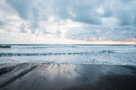 Beautiful sunset on the beach with dark clouds and sea waves.の写真素材