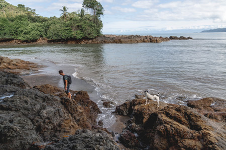 Young boy playing with a dog on the beach in Costa Rica.の写真素材