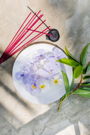 Incense sticks in a bowl with purple iris flowers and green leavesの写真素材