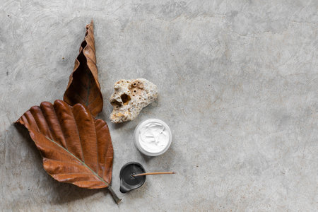 Skincare products and dry leaves on concrete background with copy spaceの写真素材