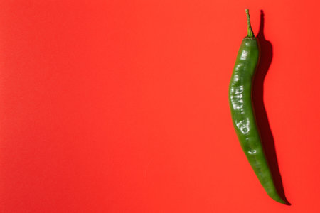 Green hot chili pepper on red background. Flat lay, top viewの写真素材