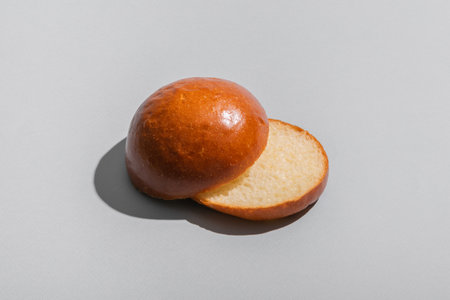 Bread cutted bun on a gray background with hard shadows. copyspace.