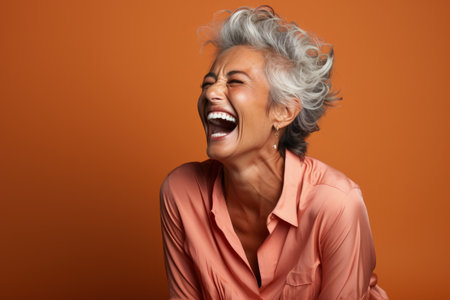 Senior woman laughing heartily isolated on a burnt sienna gradient backgroundの素材