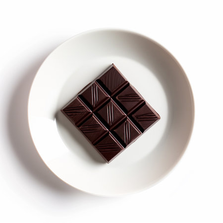 A single square of dark chocolate on a minimalist plate isolated on a transparent backgroundの素材