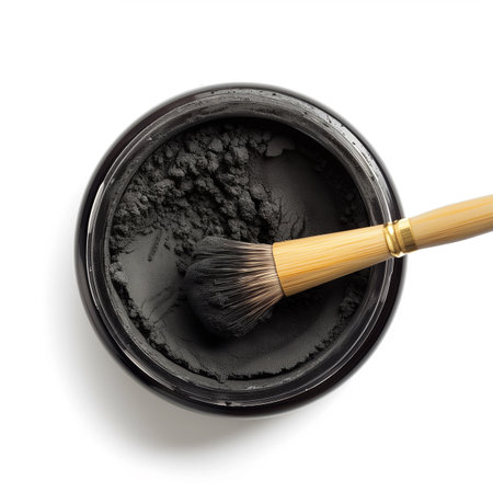 A container of activated charcoal powder with a bamboo brush top view isolated on a transparent backgroundの素材