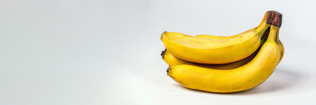 A bunch of ripe, yellow bananas on a clean white background, suitable for healthy eating concepts and food related designsの素材