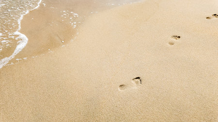 Footprints in the sand by the seaside with space for text, depicting concepts of travel, solitude,...