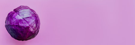 Fresh whole red cabbage on a vibrant pink background with ample copy space for text, suitable for healthy eating concepts and vegetarian recipe layoutsの写真素材