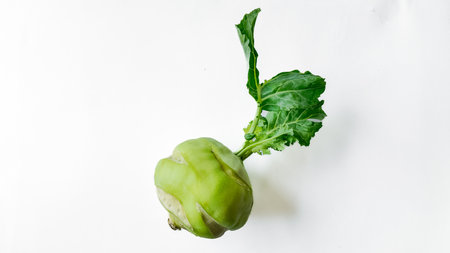 Fresh kohlrabi with leaves on a clean, white background, ideal for text overlay, representing...