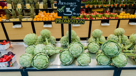 Fresh artichokes on display with promotional signage at a Parisian market, emphasizing healthy eating and local cuisine, captured in Paris, France, on April 14th, 2024のeditorial素材