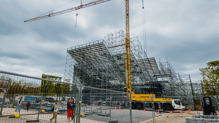 Construction site with scaffolding and crane under cloudy skies, showing urban development in Paris,...