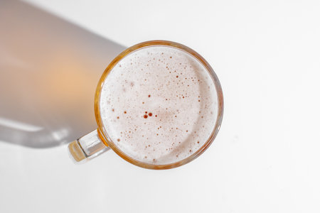 Top down view of a frothy beer mug on a white background, perfect for Oktoberfest or beer themed celebrationsの写真素材
