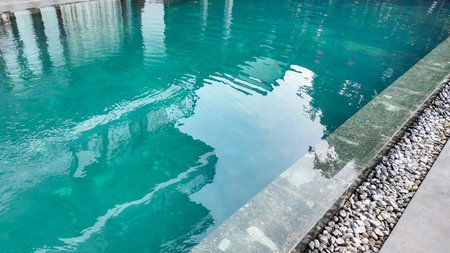 Tranquil swimming pool with turquoise water and stone edge evokes relaxation and vacation themes