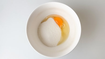 A bowl with raw egg and sugar, symbolizing baking preparation for Easter dessertsの写真素材
