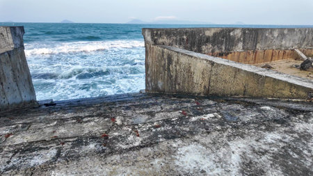 Old concrete wall on the beach. The sea waves crash against the concrete wall.の写真素材