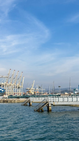 Coastal cranes dance under azure skies, a mechanical symphony whispering secrets of maritime lore and celebrationの写真素材