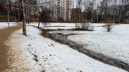 Serpentine whispers of thawing snow cradle winding stream in urban tundraの写真素材