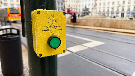 Raindrops glisten on a vibrant pedestrian button, hinting at whimsical encounters during Umbrella Day under urban rainbowsの写真素材