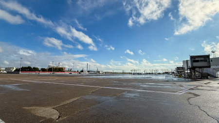 Sunlit airport tarmac glistening post rain evokes endless journey possibilities, blue sky wanderlust; ideal for Aviation Day, World Meteorological Weekの写真素材