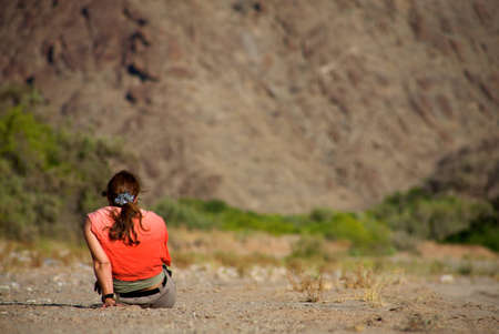 Women alone sitting in the bush somwhere in Namibia wit a red t-shirt and a blurred backgroundの写真素材