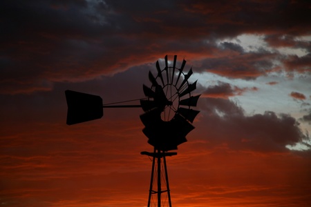 Old Farm Windmill for Pumping Water with Spinning Blades at Sunset in South Africaの写真素材