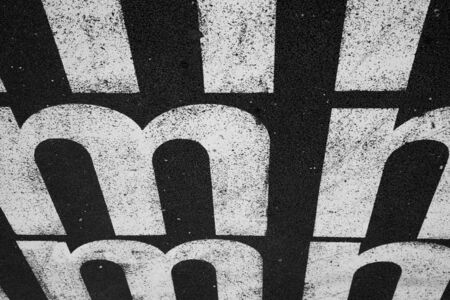 White letter m against a black toad in Lisboa, Portugal.