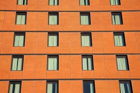 Facade of a brick office building with successive rows and floors of tinted glass windows.の写真素材