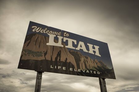 On the border of Nevada and Utah, a Welcome to Utah sign marks the separation of the two states underneath a cloud filled gray sky. Retro style imageの写真素材