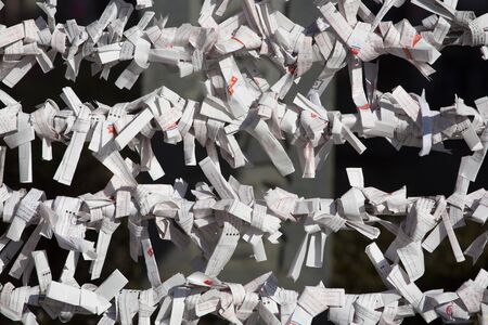Dozens of omikuji, or fortunes, are wrapped on string at a Shinto temple in Takayama, Japan.のeditorial素材