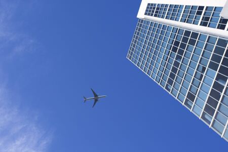 Airplane flying above a skyscraper in the sky of Miamiの写真素材