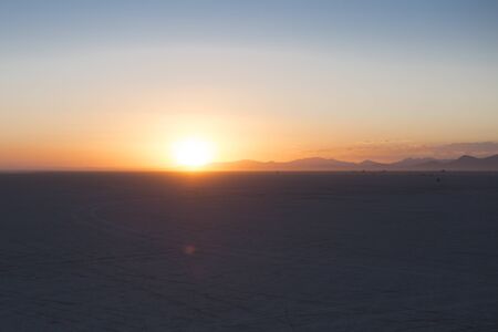 Black rock desert playa with streak of sunlight on horizonの写真素材