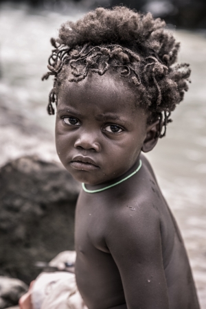 Foto de NAMIBIA,KUNENE, JANUARY 7  portrait of a young kid of the Himba people looking at the camera  The Himbas are indigenous people living in northern Namibia, in the Kunene region  formerly Kaokoland  and on the other side of the Kunene River in Angola, Janua - Imagen libre de derechos