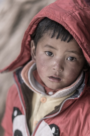 CHINA, TIBET, APRIL 4: portrait of a young kid looking at the camera, living the cold area of the Everest Base Camp in Tibet, April 19, 2013, Chinaのeditorial素材