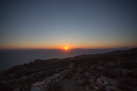 Beautiful view of the shoreline at sunset, the aegean sea, the rocky mountains and  a typical white habitat of Folegandros, an amazing island from Greece 2013.の写真素材
