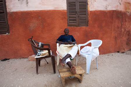 SAINT-LOUIS, SENEGAL, NOVEMBER 28: On a Sunday afternoon in Saint-Louis, a man sitting and listening to music in the street of the old city of Saint-Louis. Senegal 2010のeditorial素材