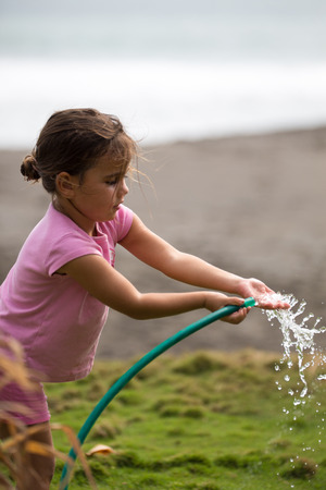 MATAPALO, COSTA RICA, MAY 3: Cute curly girl watering flowers in the garden with the Pacific in the background, Costa Rica 2012のeditorial素材