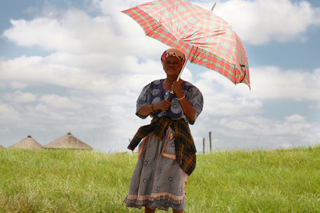 COFFEE BAY, SOUTH AFRICA, JANUARY 14: Unidentified South African woman holding an umbrella  to...