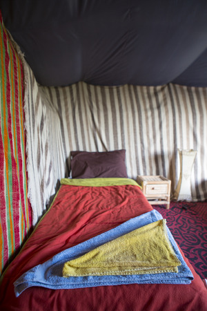 Towels on a small bed in a traditional coloured Berber tent in Morocco.の写真素材