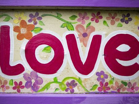 Word love painted on a wooden information board with capital bursh pink lettersの写真素材