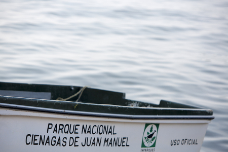 MARACAIBO, VENEZUELA, APRIL 28: Close up of small white wooden boat with the official logo and the name of National Park Cienagas de Juan Manuel with water in the background. Venezuela 2015.のeditorial素材