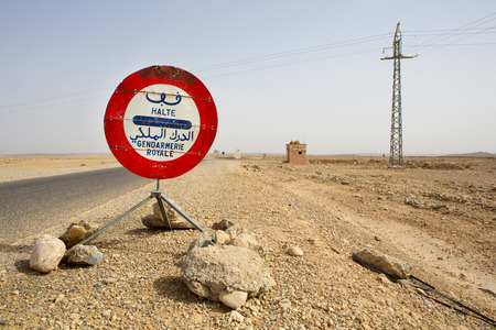 Red Stop Police sign against a blue sky on the road to Ouarzazate in Morocco. The text is written is Arabic and in French and it says "Stop".の写真素材