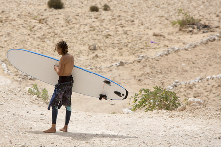 SIDI KAOUKI, MOROCCO - AUGUST 25: Unidentified Moroccan man surfer on the beach of Sidi Kaouki...