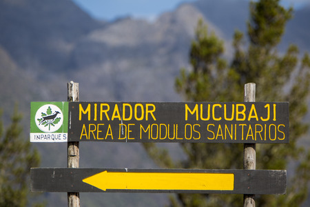 MERIDA, VENEZUELA, APRIL 30: Wooden road sign showing the direction toward the Mirador Mucubaji with the forest and mountains in the background. Venezuela 2015.のeditorial素材