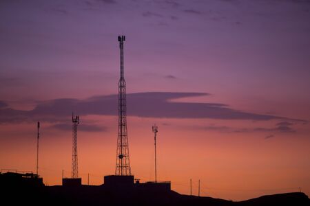 Orange purple sunset with silhouette of telecommunication towers and phone cables in Mancora. Peru