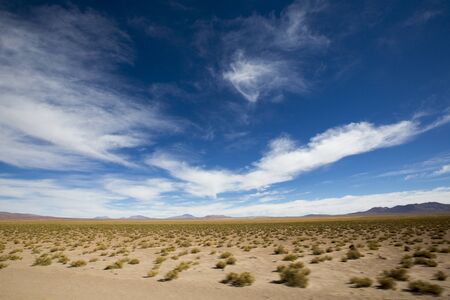 Panorama of mountains and arid landscape against a clear cloudy blue sky while driving. Boliviaの写真素材