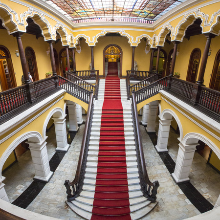 Yellow colonial interior and marble staircase with red carpet at Archbishop's Palace in Lima during the day, Peruのeditorial素材