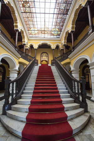 Yellow colonial interior and marble staircase with red carpet at Archbishop's Palace in Lima during the day, Peruのeditorial素材