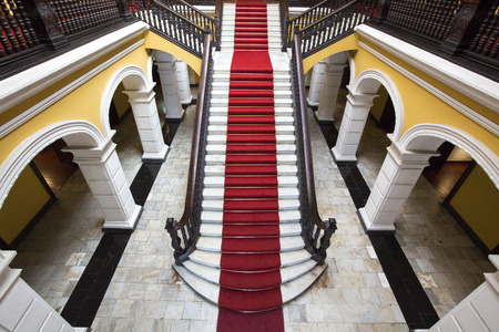 Yellow colonial interior and marble staircase with red carpet at Archbishop's Palace in Lima during the day, Peruのeditorial素材